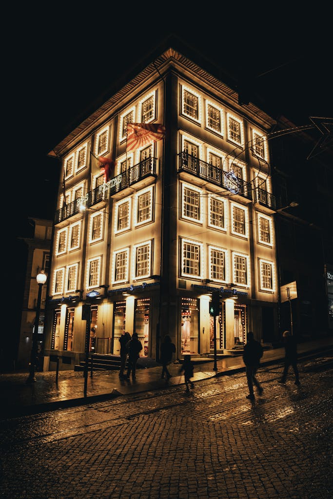 A brightly lit street view showcasing an elegant building in Porto, Portugal during nighttime.