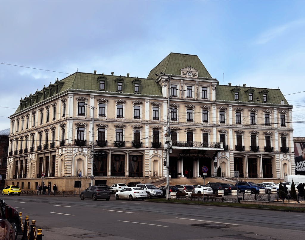 A classic European hotel with ornate architecture and green roof, seen from the street.