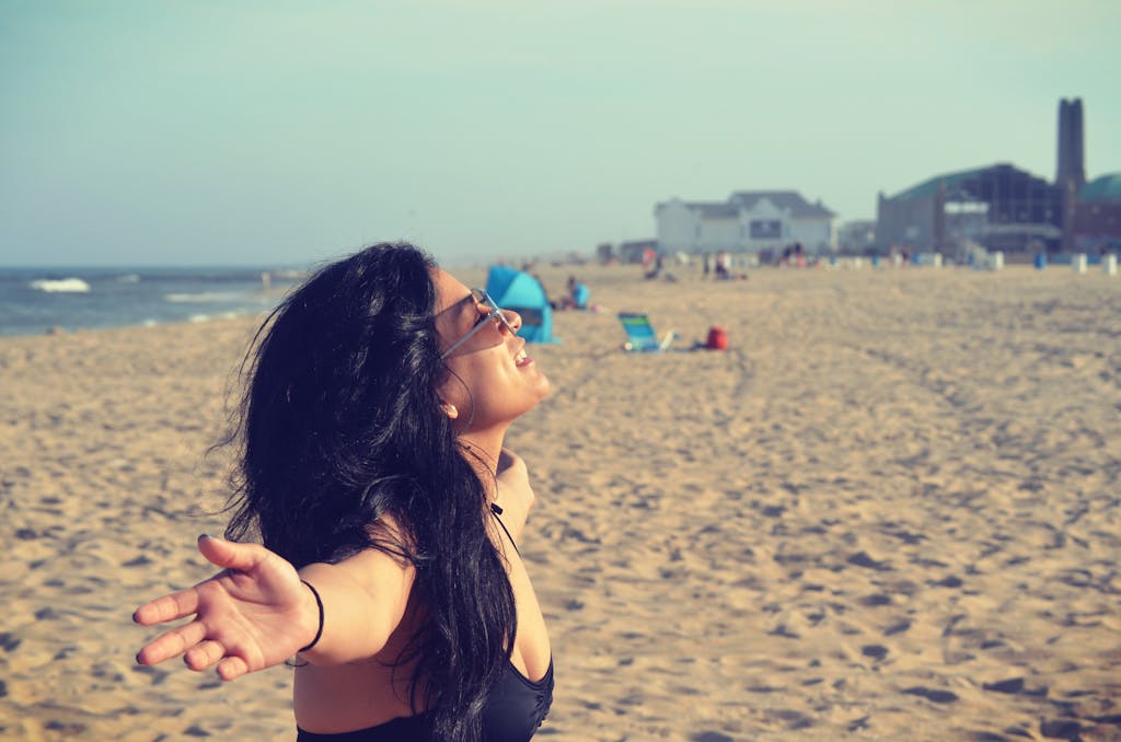 A joyful woman embracing the sun on Asbury Park beach, NJ. Summer vibes.