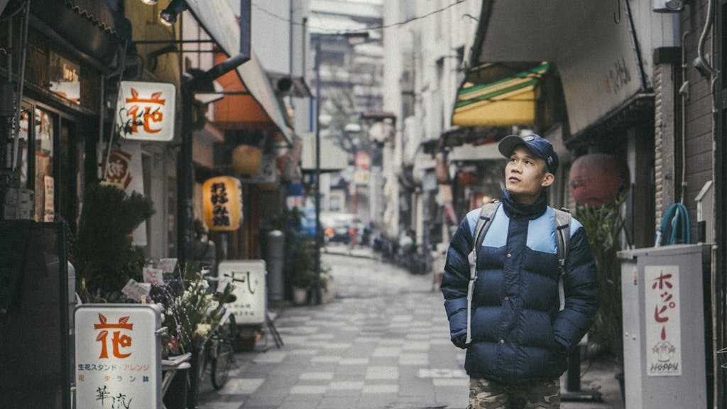A man exploring a lively shopping street filled with signage and shops in Japan.