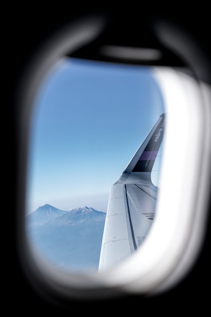A picturesque mountain view seen from an airplane window, with clear blue skies.