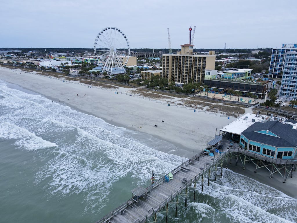 Aerial shot of Myrtle Beach with iconic pier and ferris wheel, capturing coastal beauty.