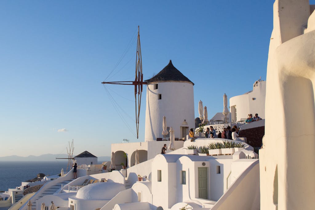 Beautiful Santorini view featuring classic white structures and windmills under a clear blue sky.