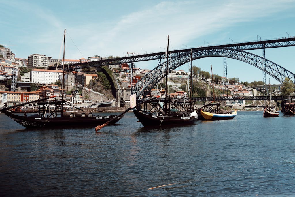 Discover the iconic Luís I Bridge in Porto with traditional sailboats on the Douro River.