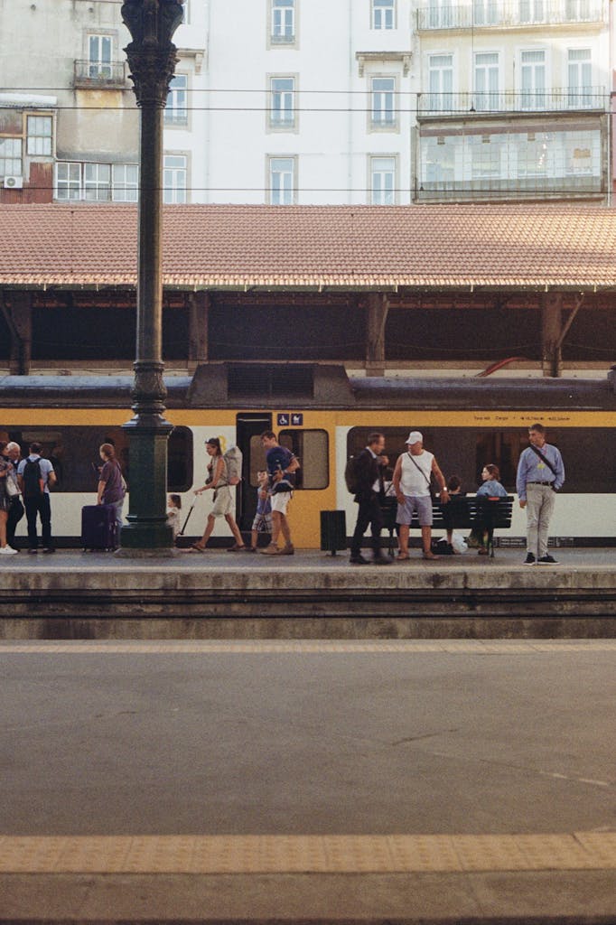 People walking at Sao Bento station, Porto, Portugal with a train in the background.
