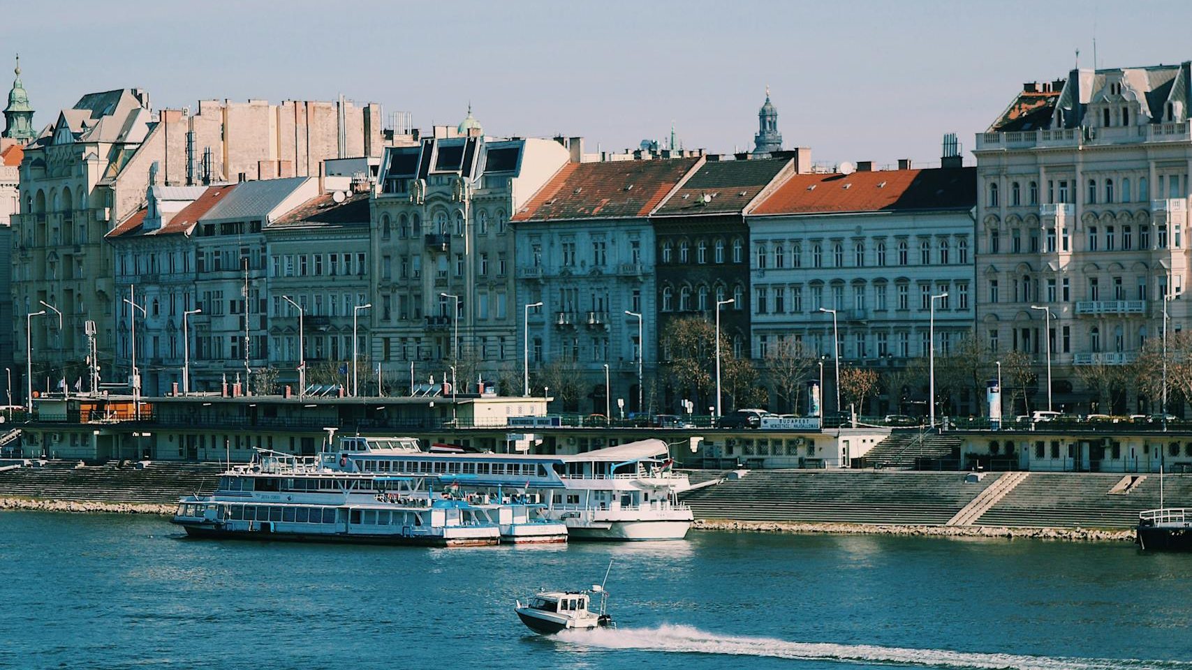 Scenic shot of ferry boats on the Danube River in Budapest, Hungary, highlighting urban architecture.