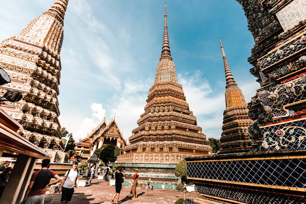 Stunning view of traditional pagodas at Wat Pho under a vibrant blue sky in Bangkok, Thailand.