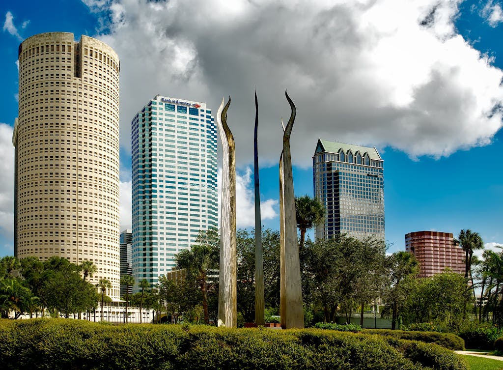 Tampa's skyline features tall skyscrapers and modern sculptures under a bright sky.