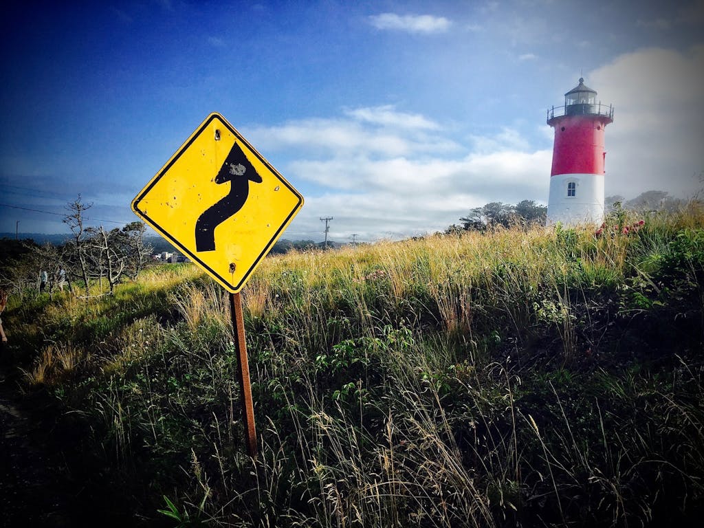 Vibrant summer scene of a lighthouse and road sign in Barnstable, MA.