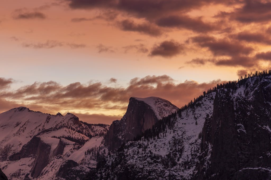 Breathtaking view of Half Dome at sunset in Yosemite National Park. Captured in winter with snow-capped peaks.
