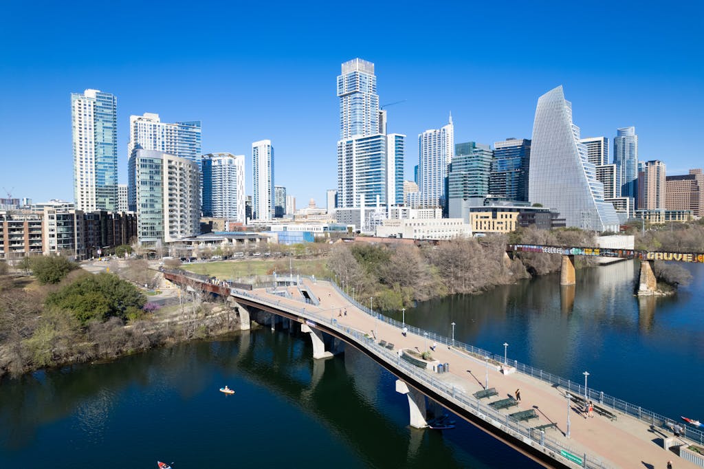 Panoramic view of Austin's skyline, featuring modern skyscrapers, a bridge, and a serene river.