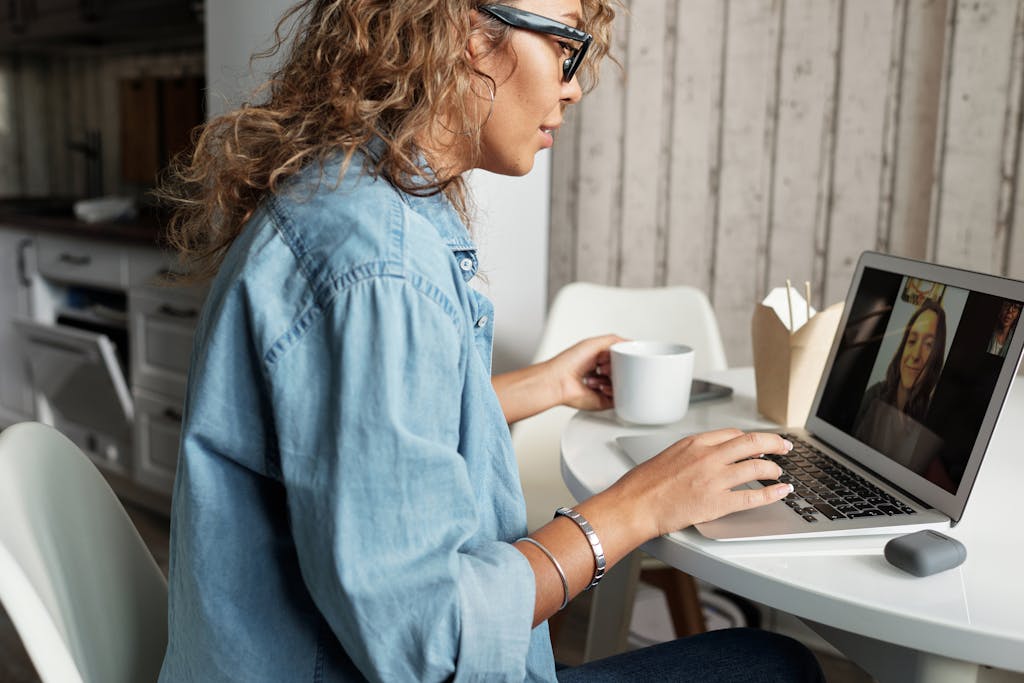 Woman enjoying a video call with a friend, sipping coffee at home.